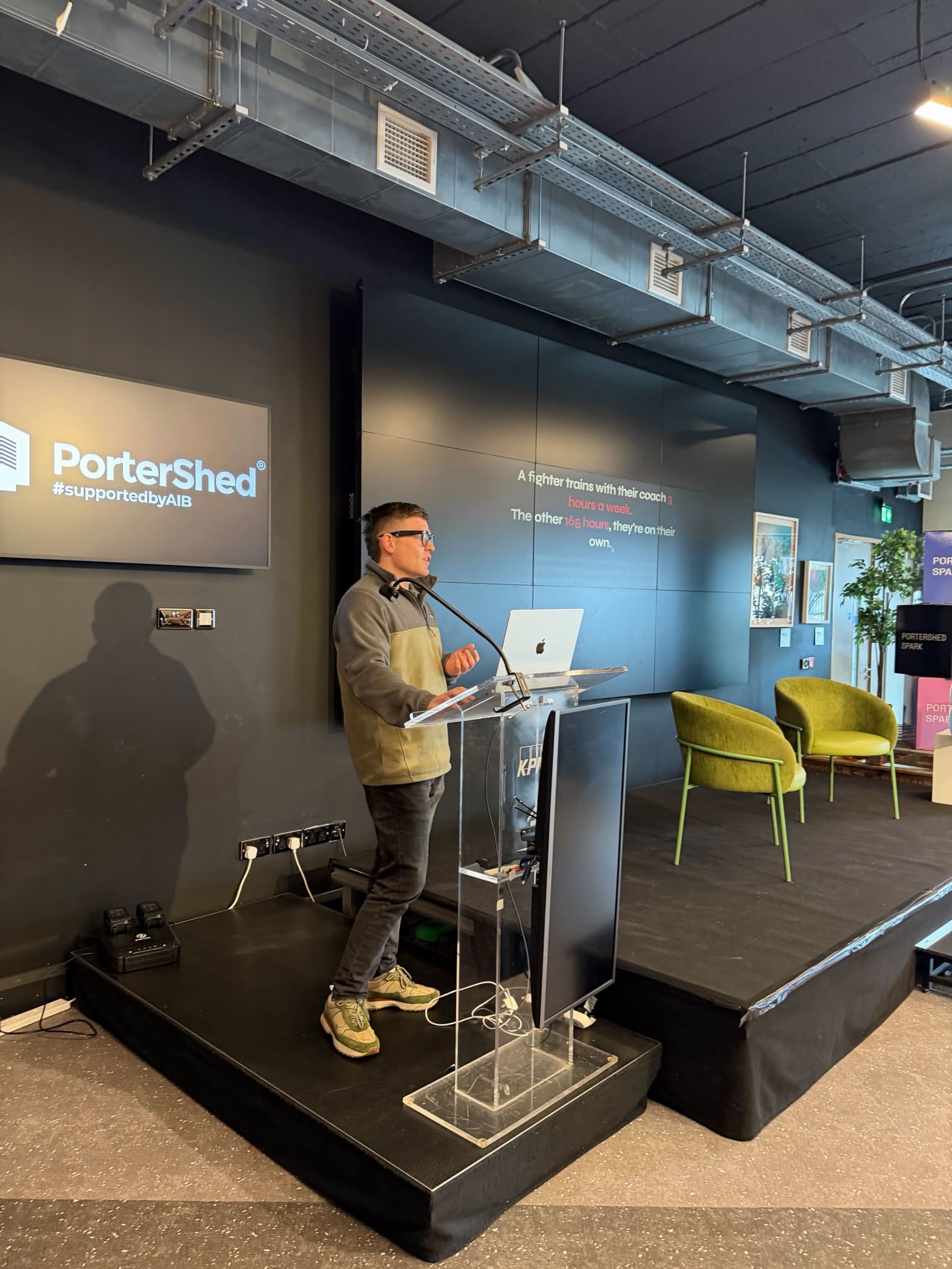 Kevin presenting Sensei AI at a lectern on the PorterShed stage